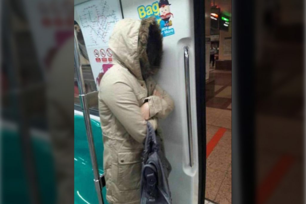 A passenger on Singapore MRT train wearing very thick furry jacket because it was very cold due to Monsoon Surge